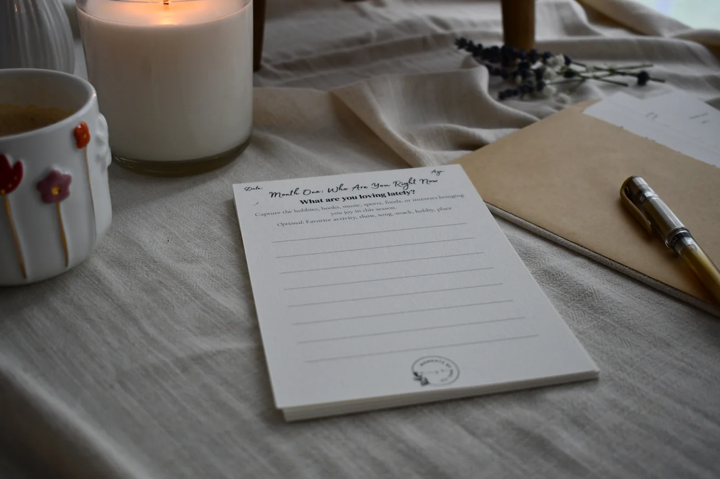Becoming You prompt card staged with a mug, candle, envelope, and pen.
