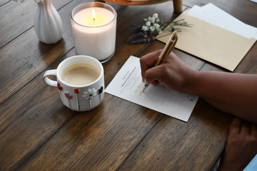 If You Could Ask Me prompt card being filled out beside coffee and a candle.
