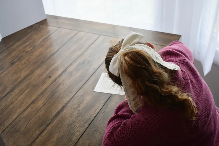 Child writing with a Moments by Mail Co. keepsake prompt.