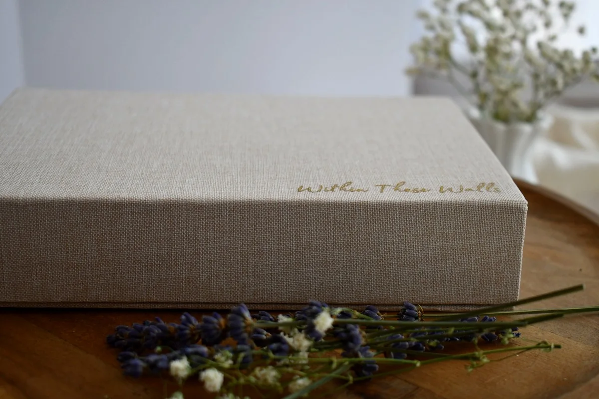Within These Walls linen keepsake box styled with lavender and white flowers.